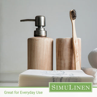 Silver magnolia guest towels in a bathroom with a soap dispenser and a toothbrush behind them.