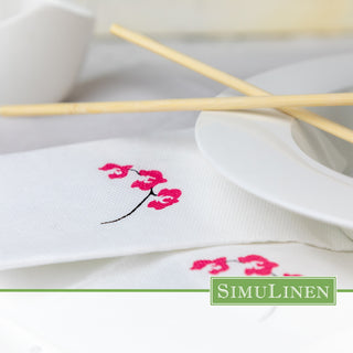 SimuLinen ClassicPoint Orchid Disposable Napkins under a dinner plate.