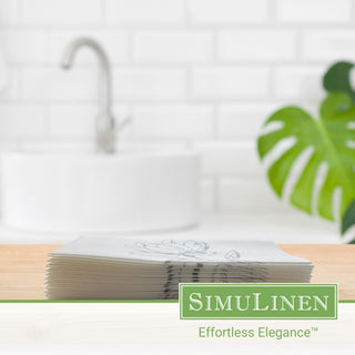 Image of silver magnolia guest towels on a wooden board with a bathroom sink in the background.