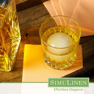Image of a glass of whiskey on top of SimuLinen apricot beverage napkins.