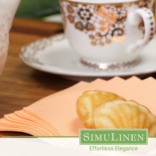 An image of SimuLinen apricot beverage napkins with some tea cookies and a tea cup in the background.