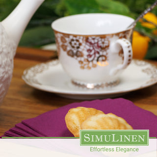 Image of aubergine beverage napkins with a fancy tea cup in the background.