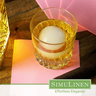 SimuLinen bubblegum pink beverage napkins underneath a whiskey glass.