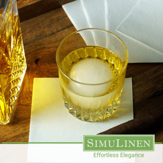 SimuLinen light grey disposable cocktail napkins with a glass of whiskey on top.