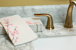 Image of Cherry Blossom guest towels on a marbled bathroom sink with gold colored faucet and handles.